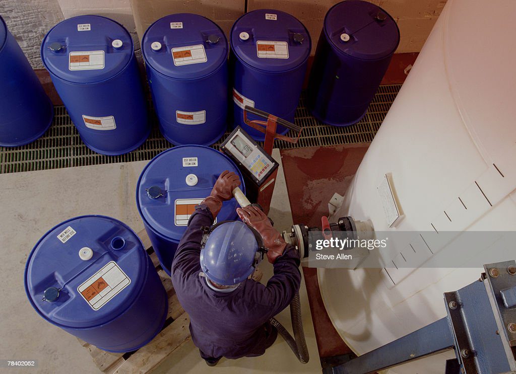 man filling chemical storage containers - tanque azul fotografías e imágenes de stock