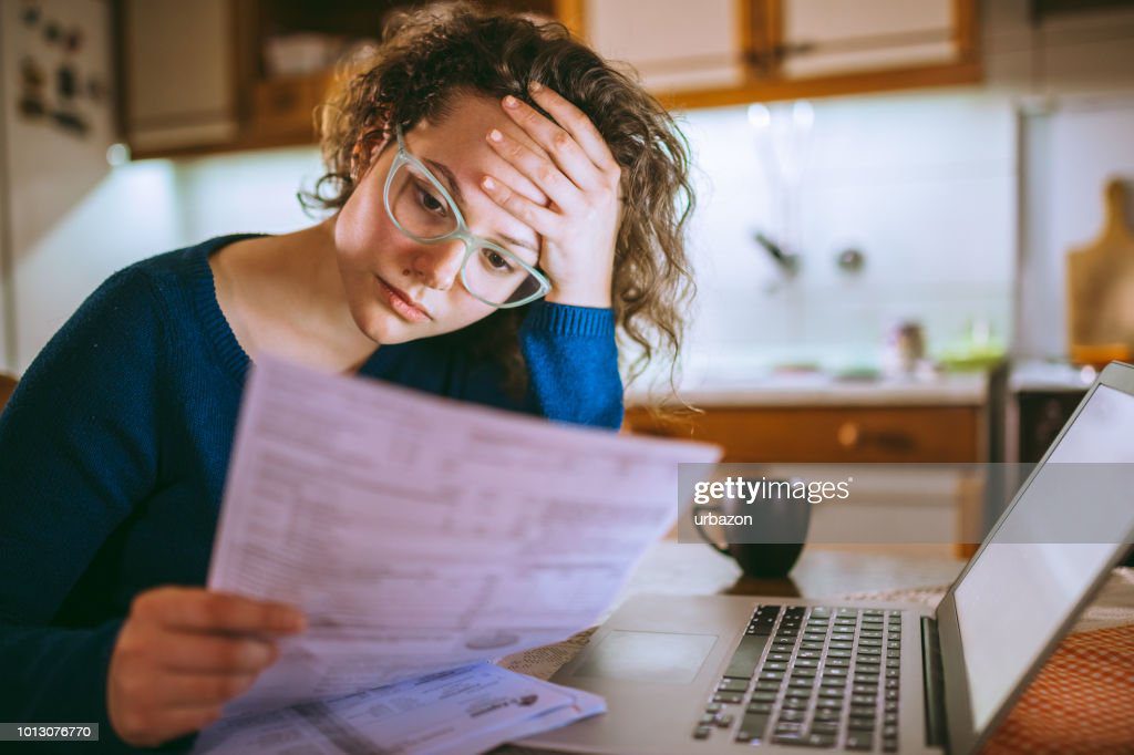 mujer pasando por facturas, mirando preocupado - factura fotografías e imágenes de stock