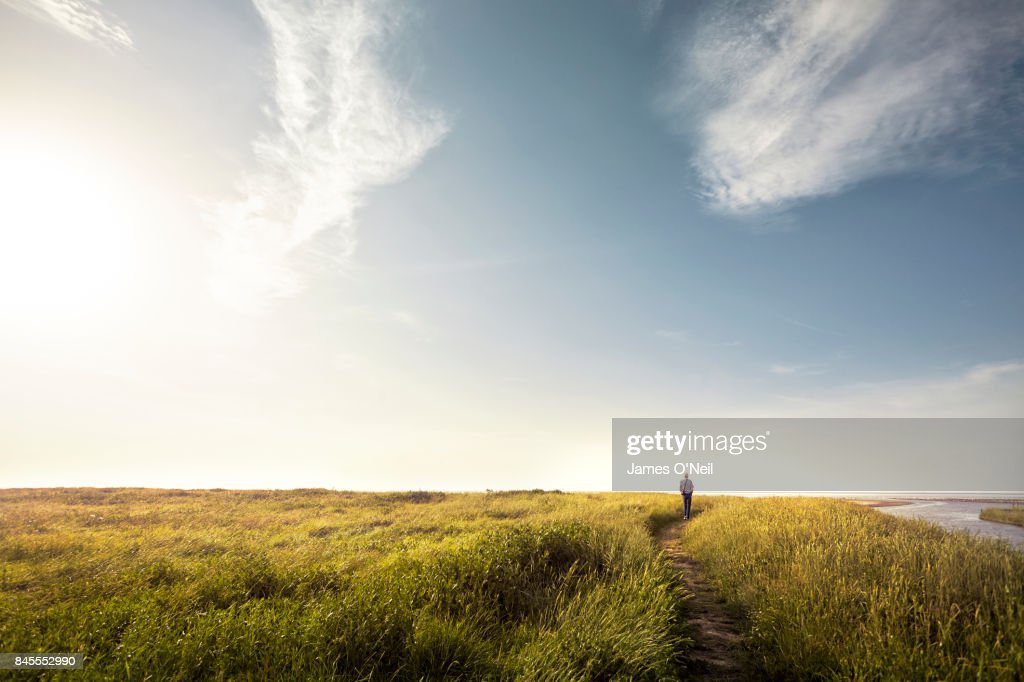 man walking alone down country path at sunset - lugar lejos fotografías e imágenes de stock