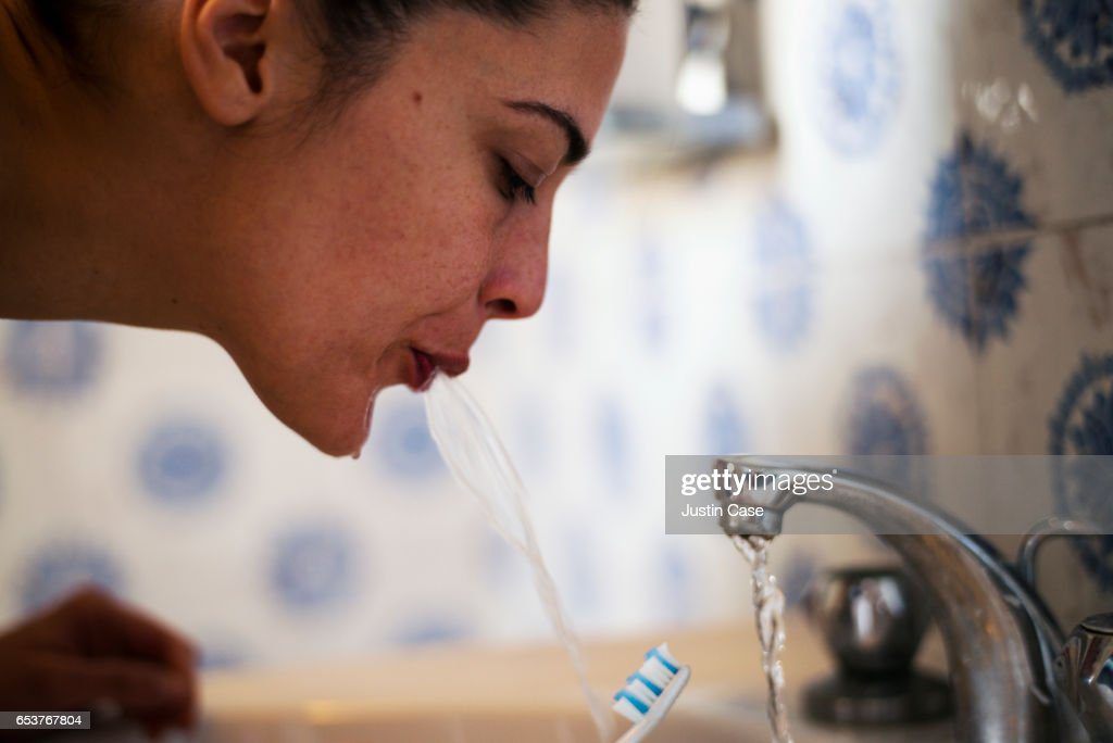 woman spitting out water after brushing her teeth - escupir fotografías e imágenes de stock