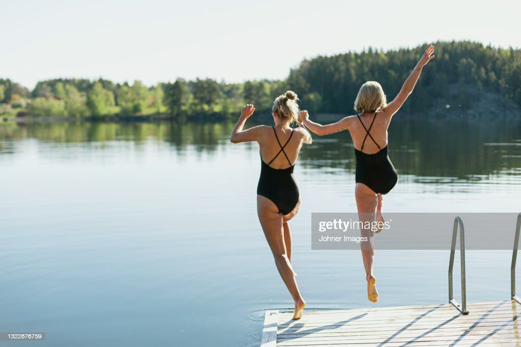 women jumping into lake from deck - bañarse junto fotografías e imágenes de stock
