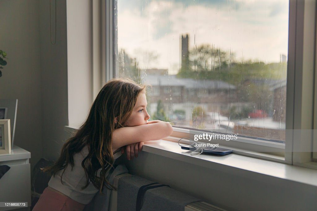 young girl looking out of window on a rainy day - tristeza fotografías e imágenes de stock