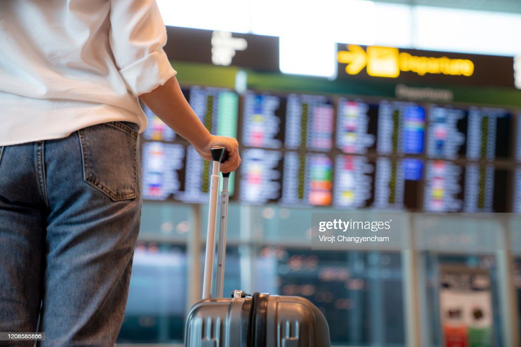 female traveller standing in front of flight display schedule in the international airport - retraso fotografías e imágenes de stock