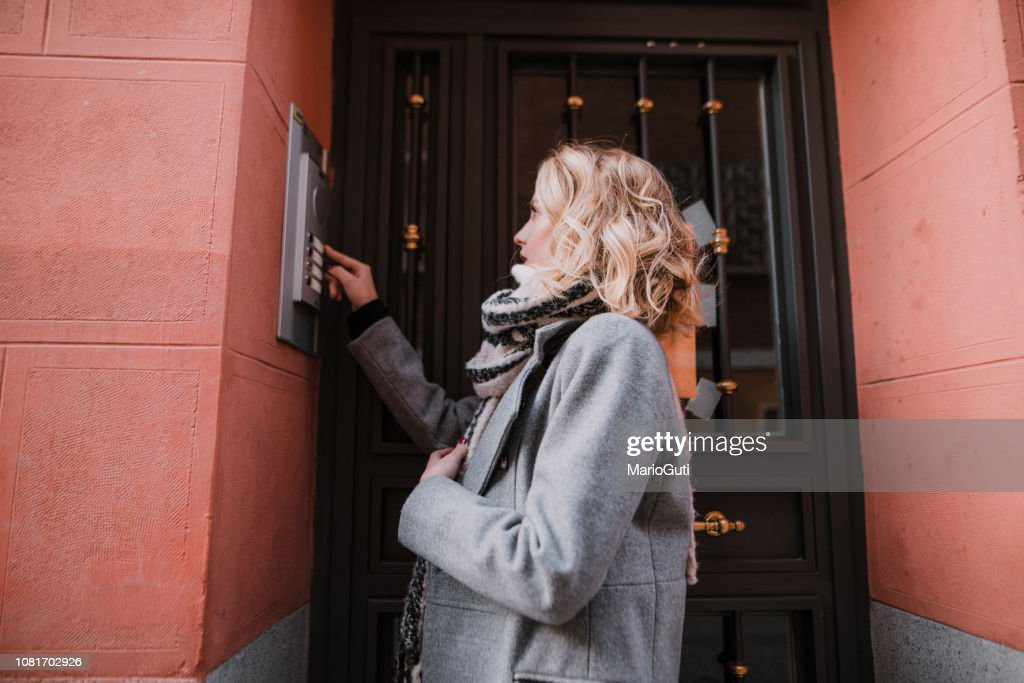 mujer tocando una campana de apartamento - llamada fotografías e imágenes de stock