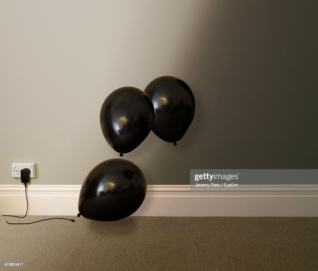 black balloons by charger connected to outlet - globo negro fotografías e imágenes de stock