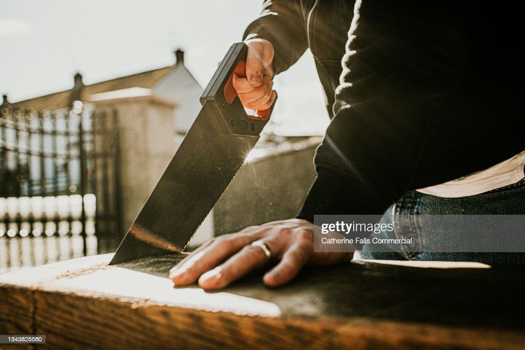 back-lit close-up of a man using a handsaw - sierra electrica fotografías e imágenes de stock
