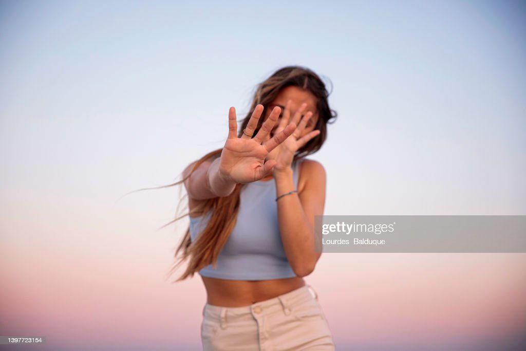 portrait of woman covering her face with her hand at sunset - verguenza fotografías e imágenes de stock