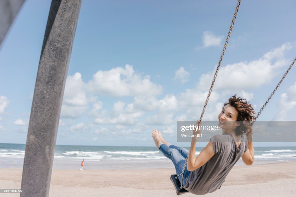 happy woman on a swing on the beach - columpio fotografías e imágenes de stock