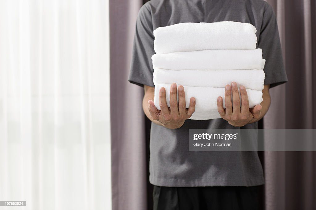 male housekeeper in hotel holding towels - toalla fotografías e imágenes de stock