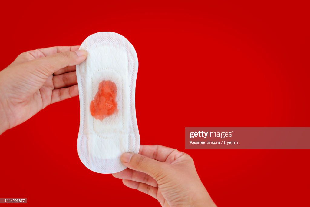 cropped hands of woman holding sanitary pad with menstruation over red background - toalla sanitaria sangre fotografías e imágenes de stock