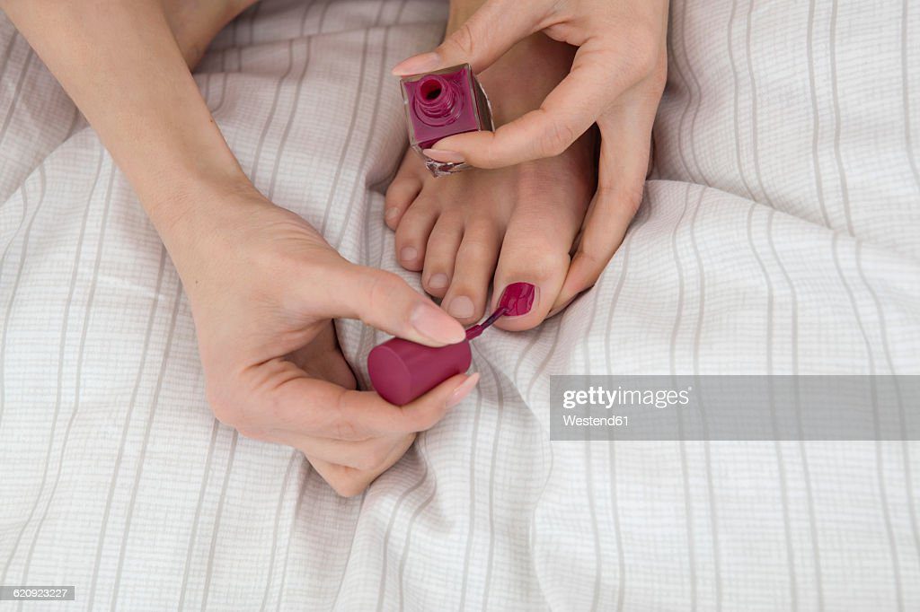 young woman on bed painting her toenails - uñas de los pies fotografías e imágenes de stock