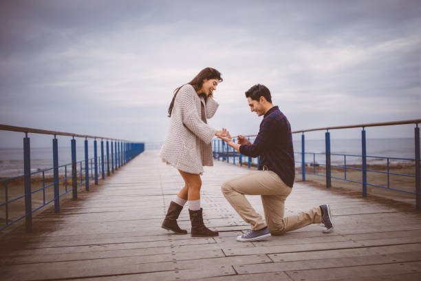 hombre en una rodilla, propone a la novia en un muelle - compromiso fotografías e imágenes de stock