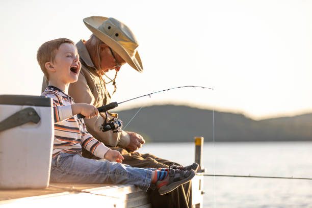abuelo y nieto pescando al atardecer en verano - pescar fotografías e imágenes de stock