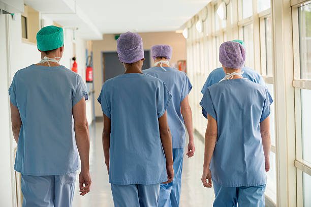 rear view of a medical team walking in the corridor of a hospital - enfermera fotografías e imágenes de stock