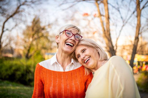 dos mujeres mayores riéndose del parque - pasado amigo fotografías e imágenes de stock