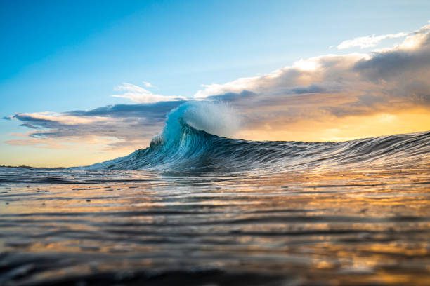 colorida ola alcanzando un pico en una llamarada con tormenta al amanecer - paisaje fotografías e imágenes de stock