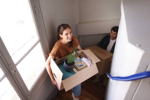 a happy young couple moving into a new apartment - mudanza fotografías e imágenes de stock