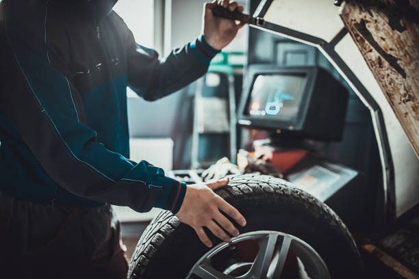 mecánico balanceando un neumático en el taller de reparación de automóviles - neumatico fotografías e imágenes de stock