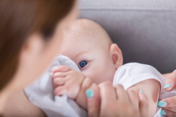 adorable bebé de ojo azul mira mamá durante la lactancia - amamantar fotografías e imágenes de stock