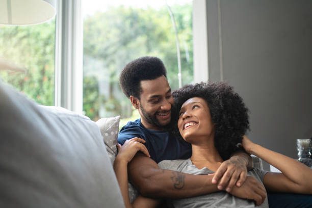 pareja africana acostada y teniendo momento romántico en el sofá - novio fotografías e imágenes de stock